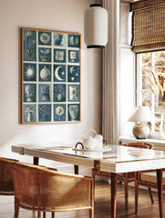 Blue and white illustrative grid art print featuring cats, flowers, moon, stars, and abstract shapes, in a styled room mockup