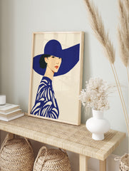 Illustrative art print of a woman in a wide-brimmed blue hat and patterned blue top against a cream background. Blue Hat Woman Wall Art. - Image 3