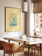 Illustrative blue heron standing amongst blue cattails and reeds with golden flourishes on a pale, in a styled room mockup