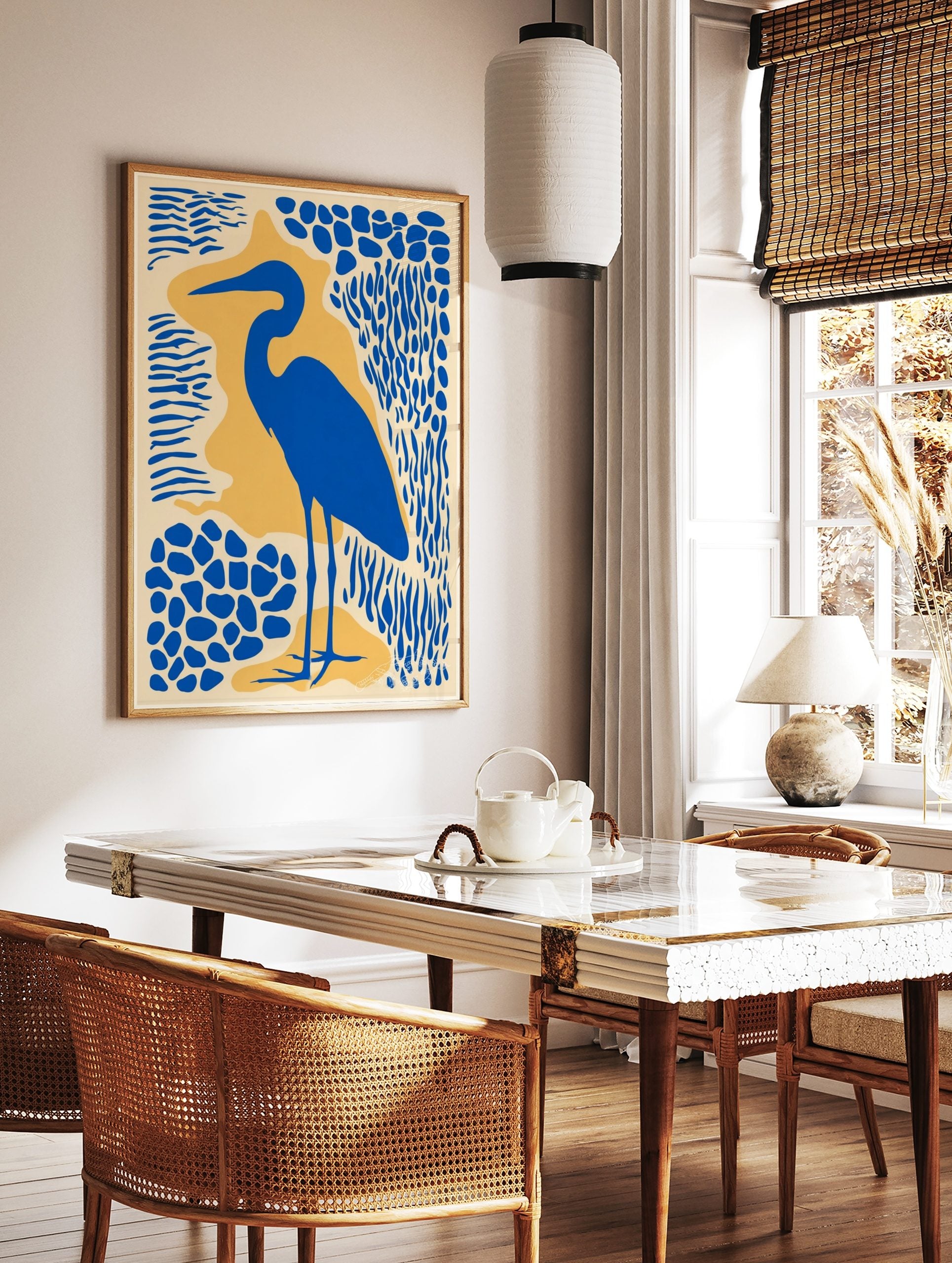 Blue heron bird silhouette art print with abstract blue and yellow shapes on a cream background, in a styled room mockup