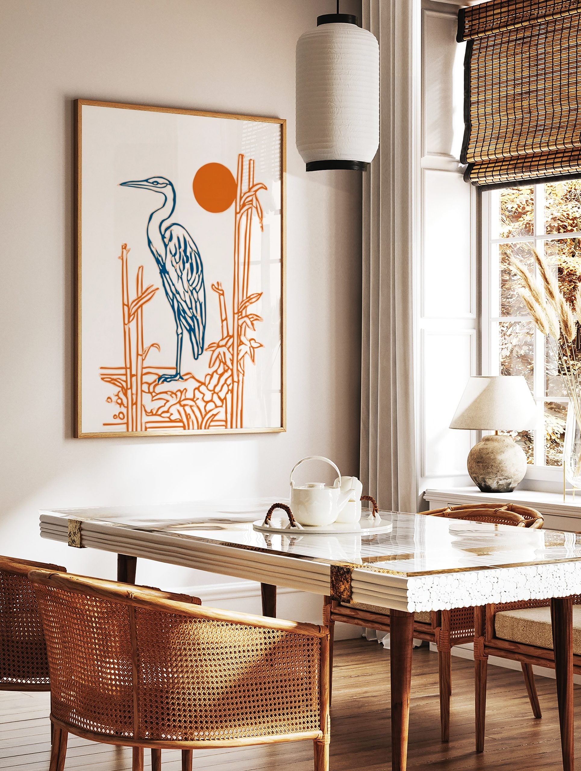 Illustrative blue heron standing by orange bamboo stalks with a vibrant orange sun on a white, in a styled room mockup