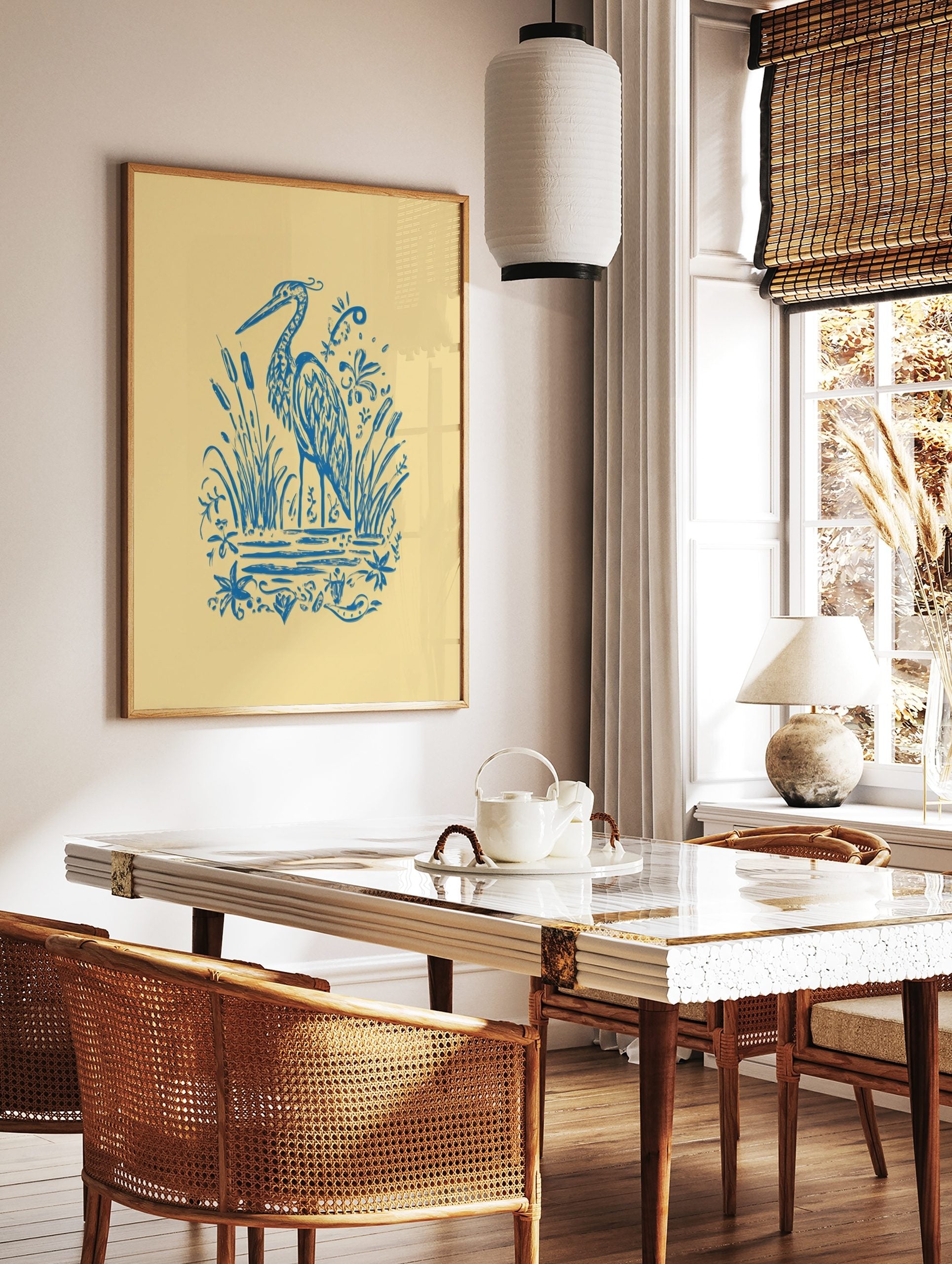 Blue illustrative heron standing among cattails and water plants on a light yellow background, in a styled room mockup