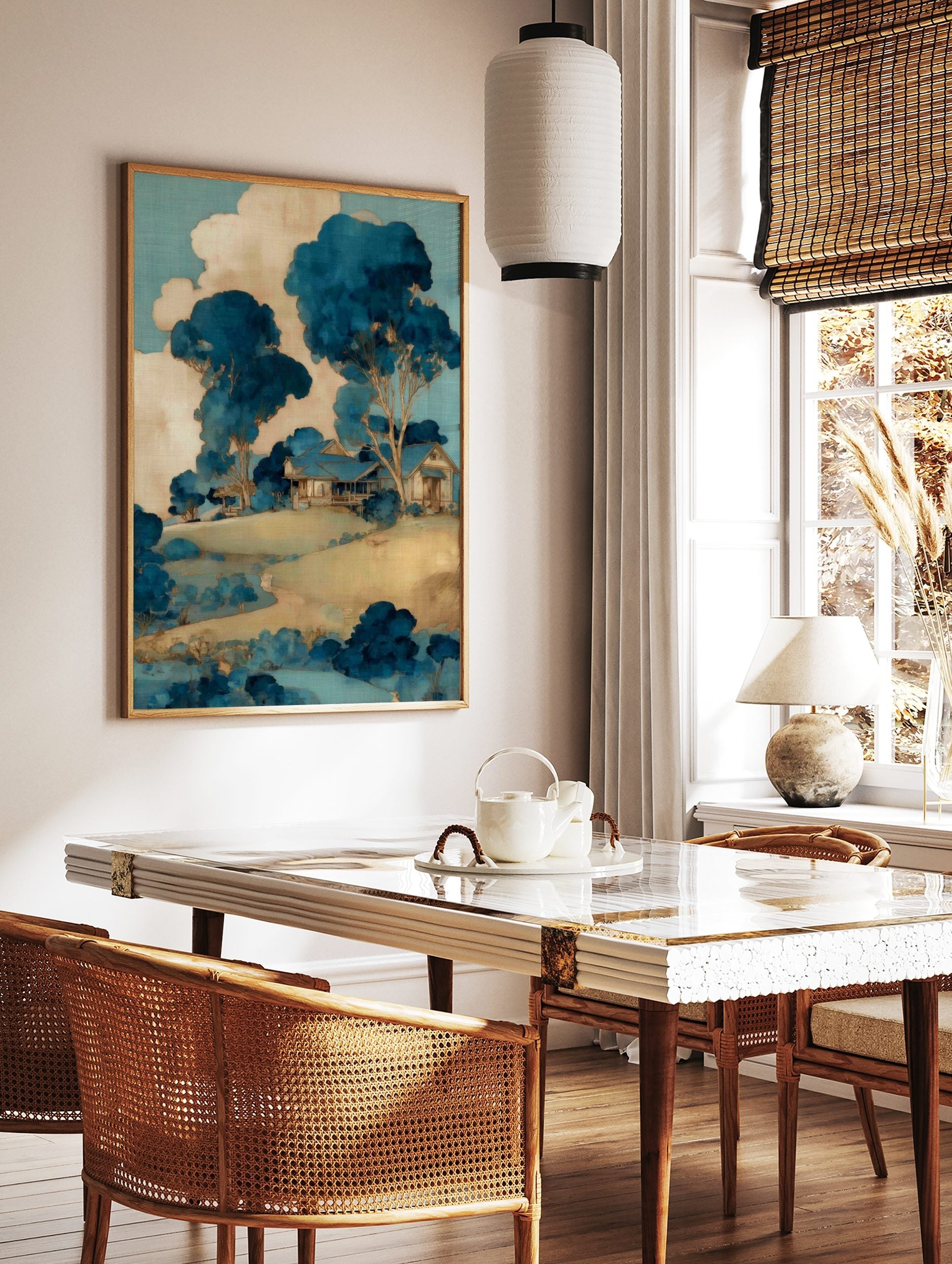 Illustrative blue and beige landscape art print with a house on a hill, surrounded by stylised, in a styled room mockup