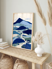 Illustrative blue landscape wall art print featuring mountains, hills, a winding path with figures, and trees. - Image 3