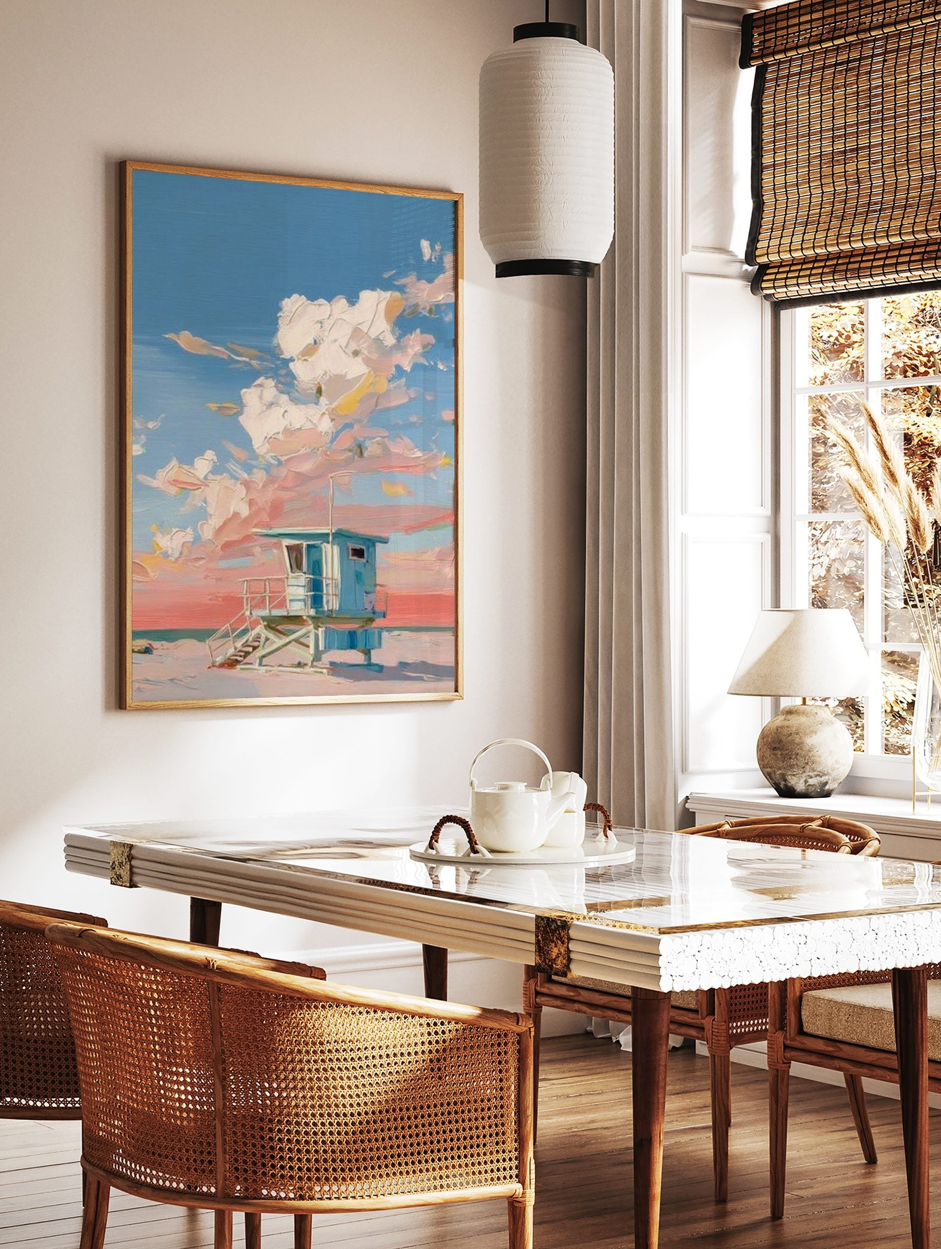 Blue lifeguard hut on a sandy beach with thick impasto clouds in a pink and blue sky, in a styled room mockup