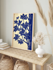 Illustrative blue maple leaves and tree trunk art print on a cream background, portrait, in an alternate framed mockup