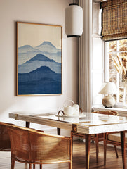 Minimalist mountain landscape wall art with layered blue silhouettes and fabric texture on a light, in a styled room mockup