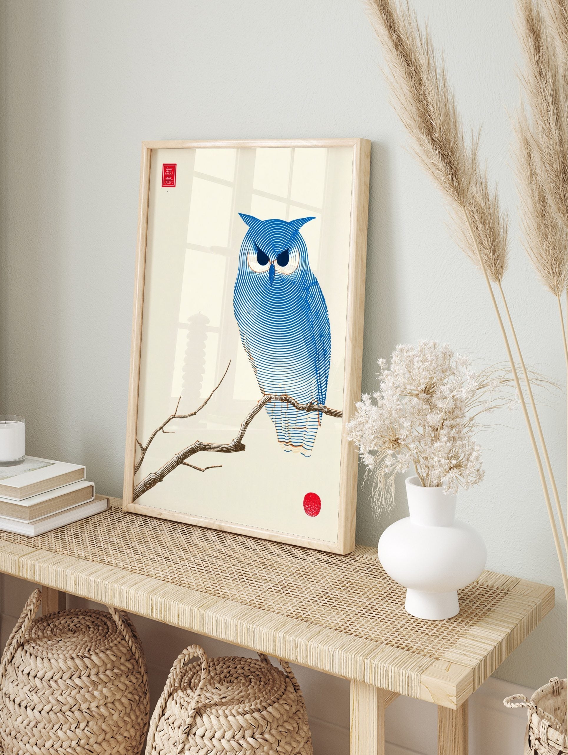 Blue owl illustration on a branch with concentric lines, red seal, and red circle on, in an alternate framed mockup