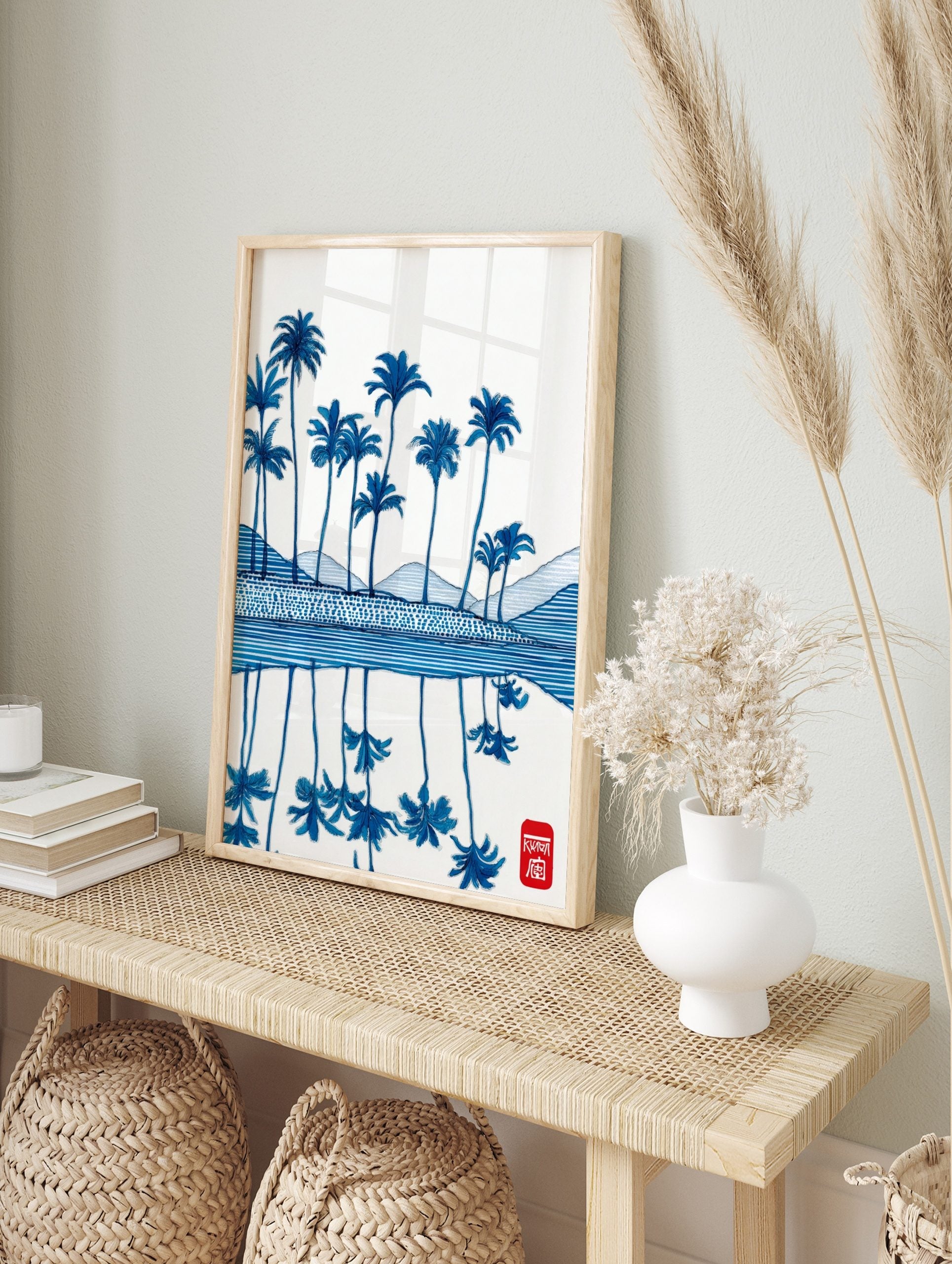 Illustrative blue palm trees and reflections on water, with patterned hills and a red seal, in an alternate framed mockup