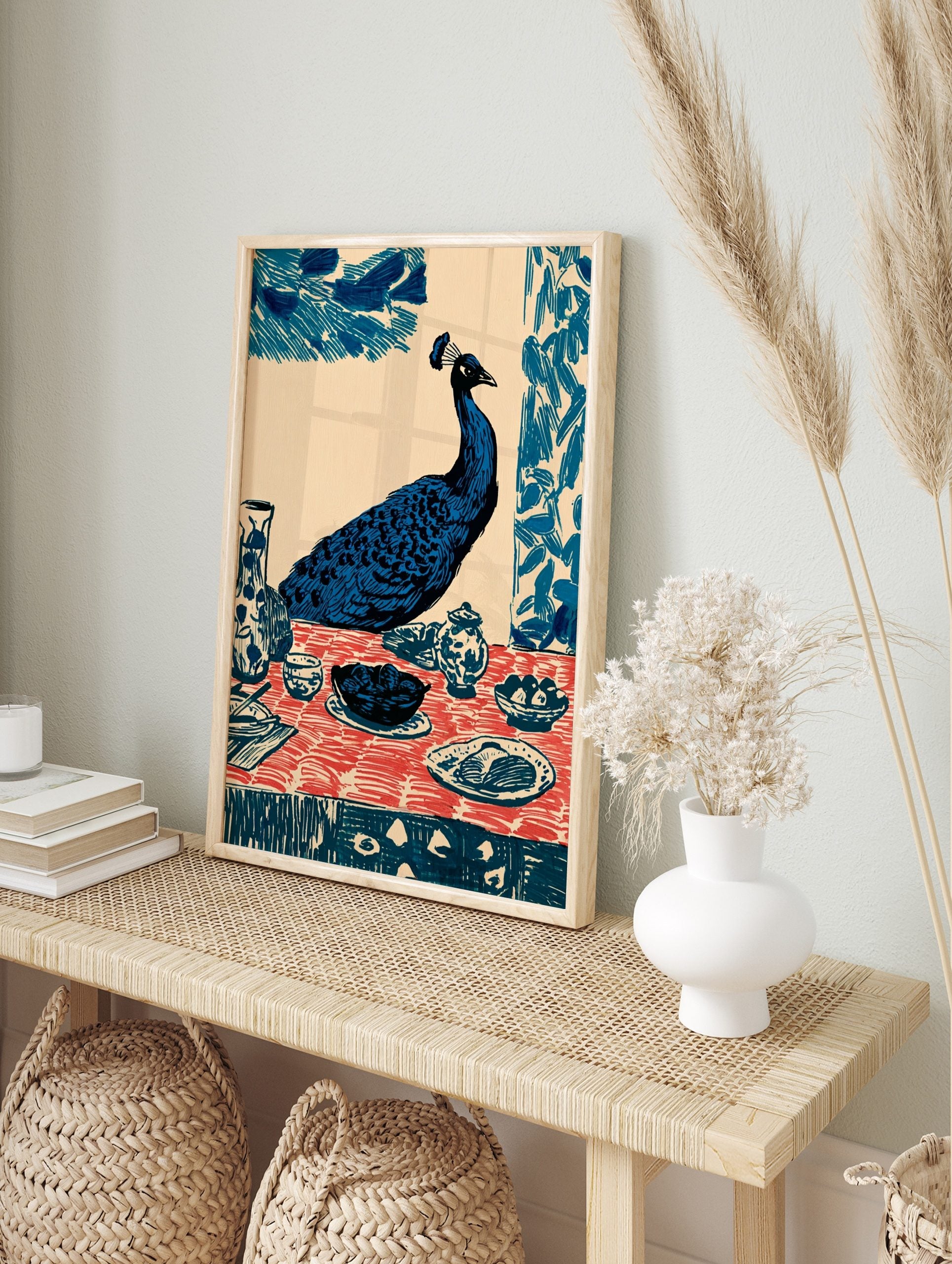 Illustrative blue peacock seated at a dining table with red patterned tablecloth and ceramic, in an alternate framed mockup