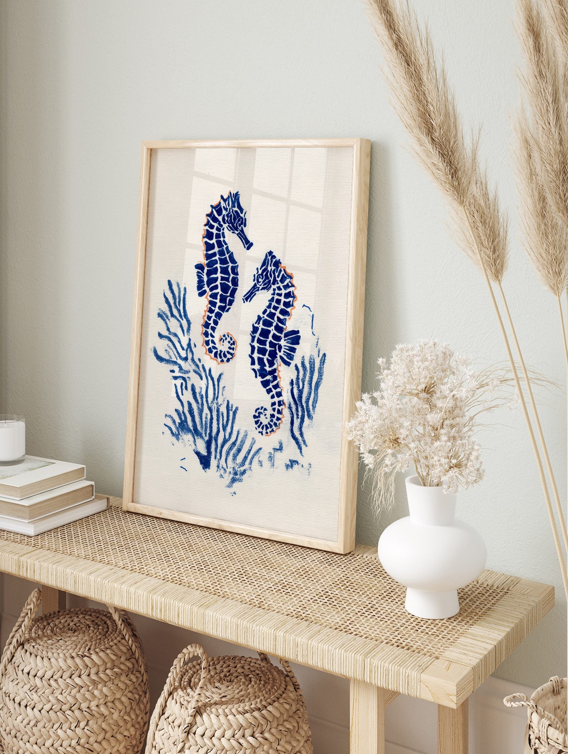 Two blue seahorses with orange outlines, surrounded by blue coral on a white background, in, in an alternate framed mockup