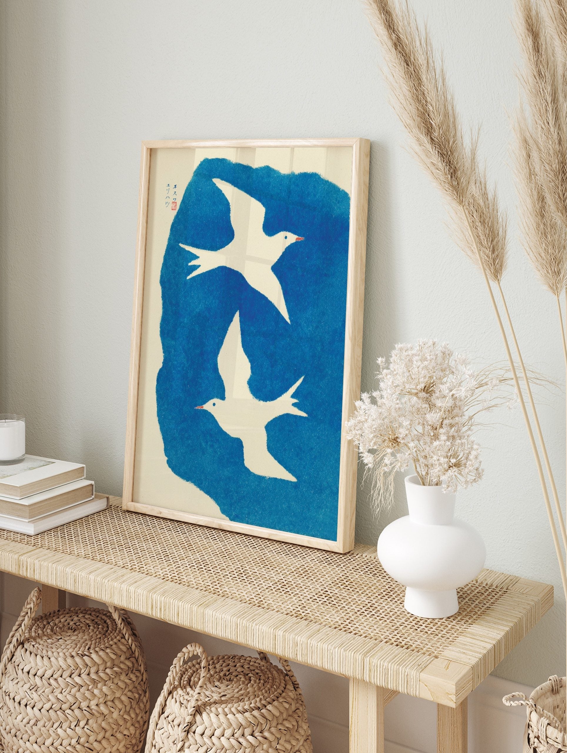 Two white illustrative birds flying against a textured blue background with Japanese text and, in an alternate framed mockup