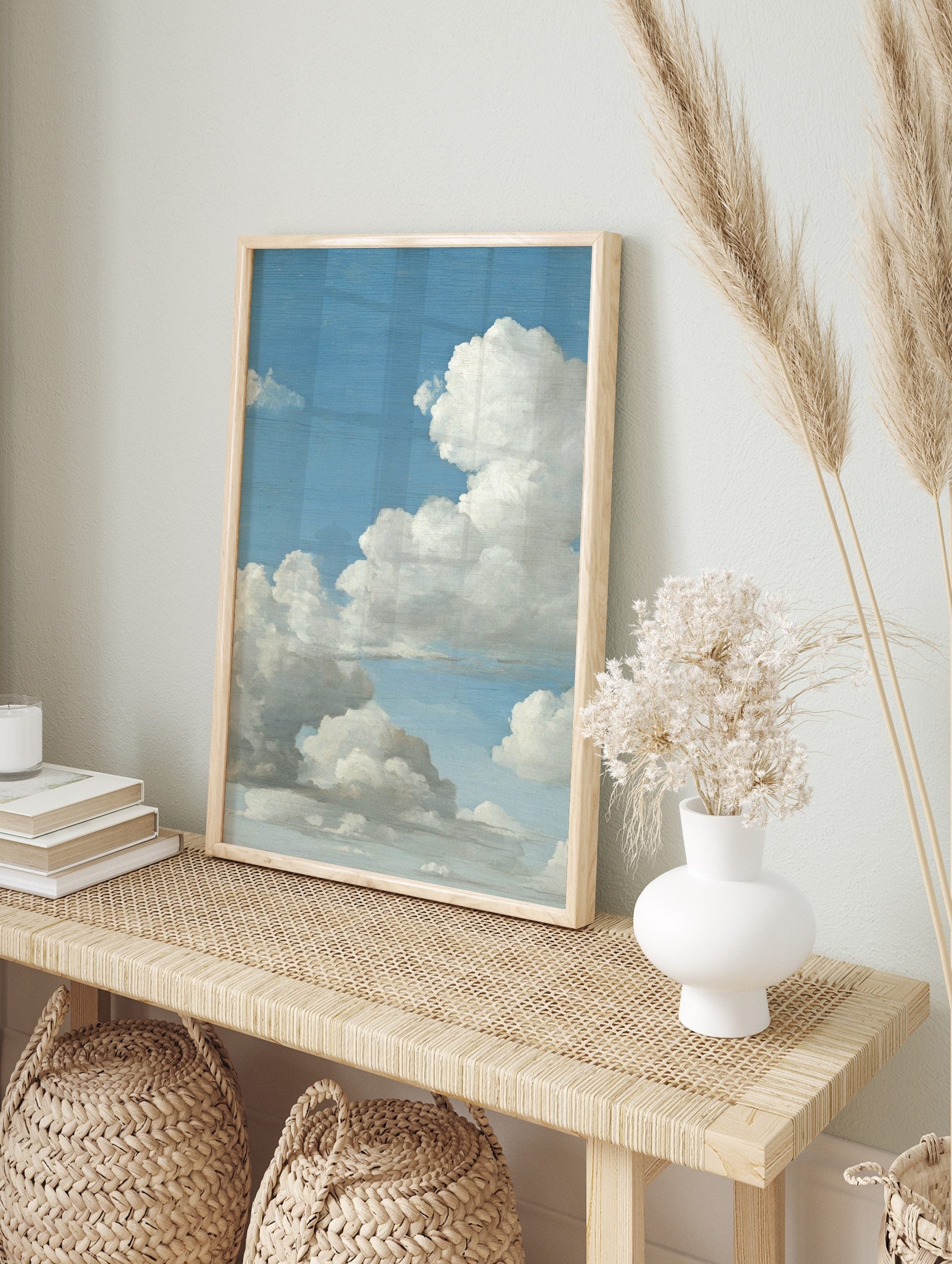 Close-up of a painting depicting a vast blue sky filled with large, fluffy white and grey, in an alternate framed mockup