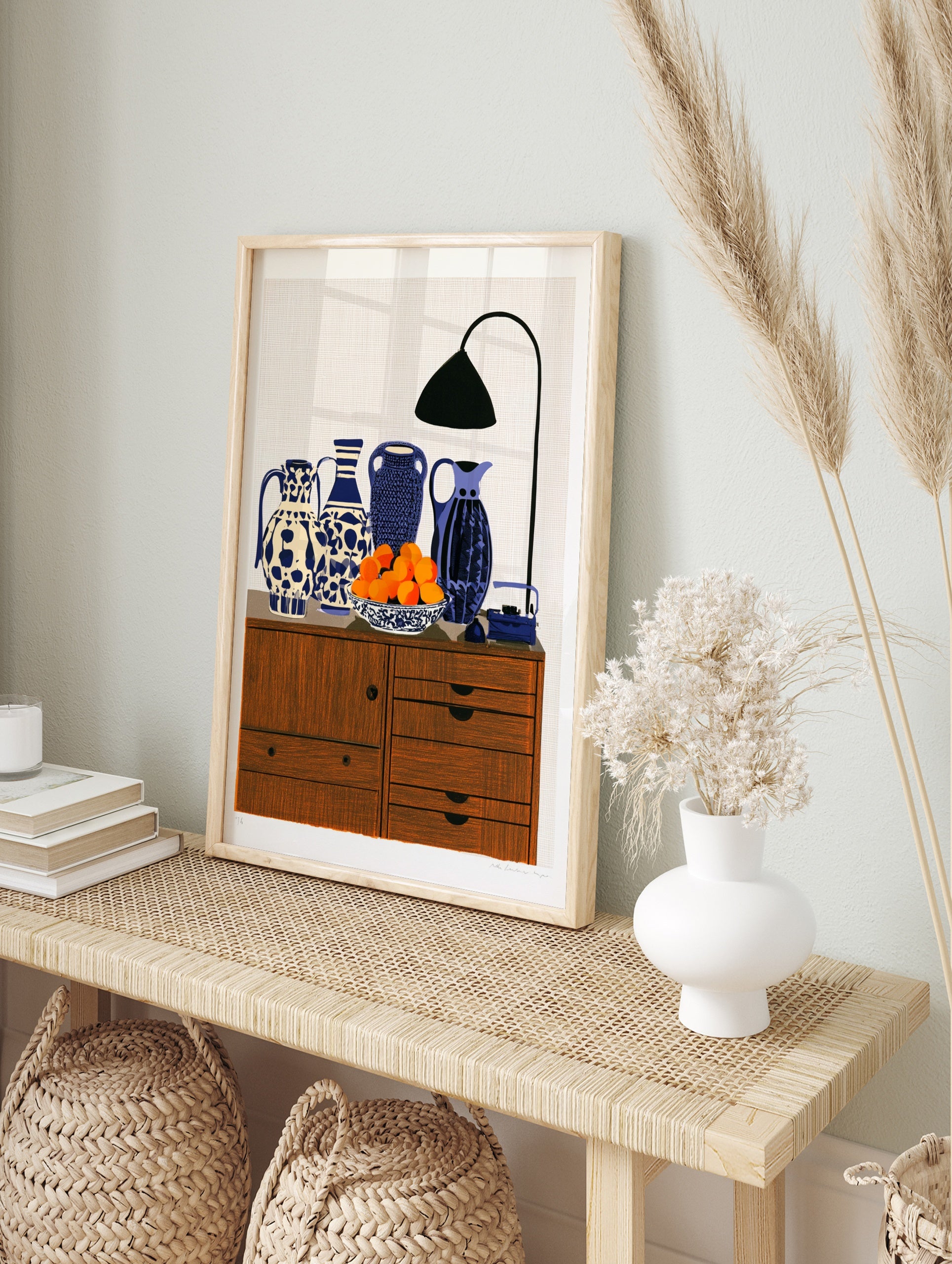 Still life art print featuring four patterned blue and white vases, a bowl of oranges, and a, in an alternate framed mockup