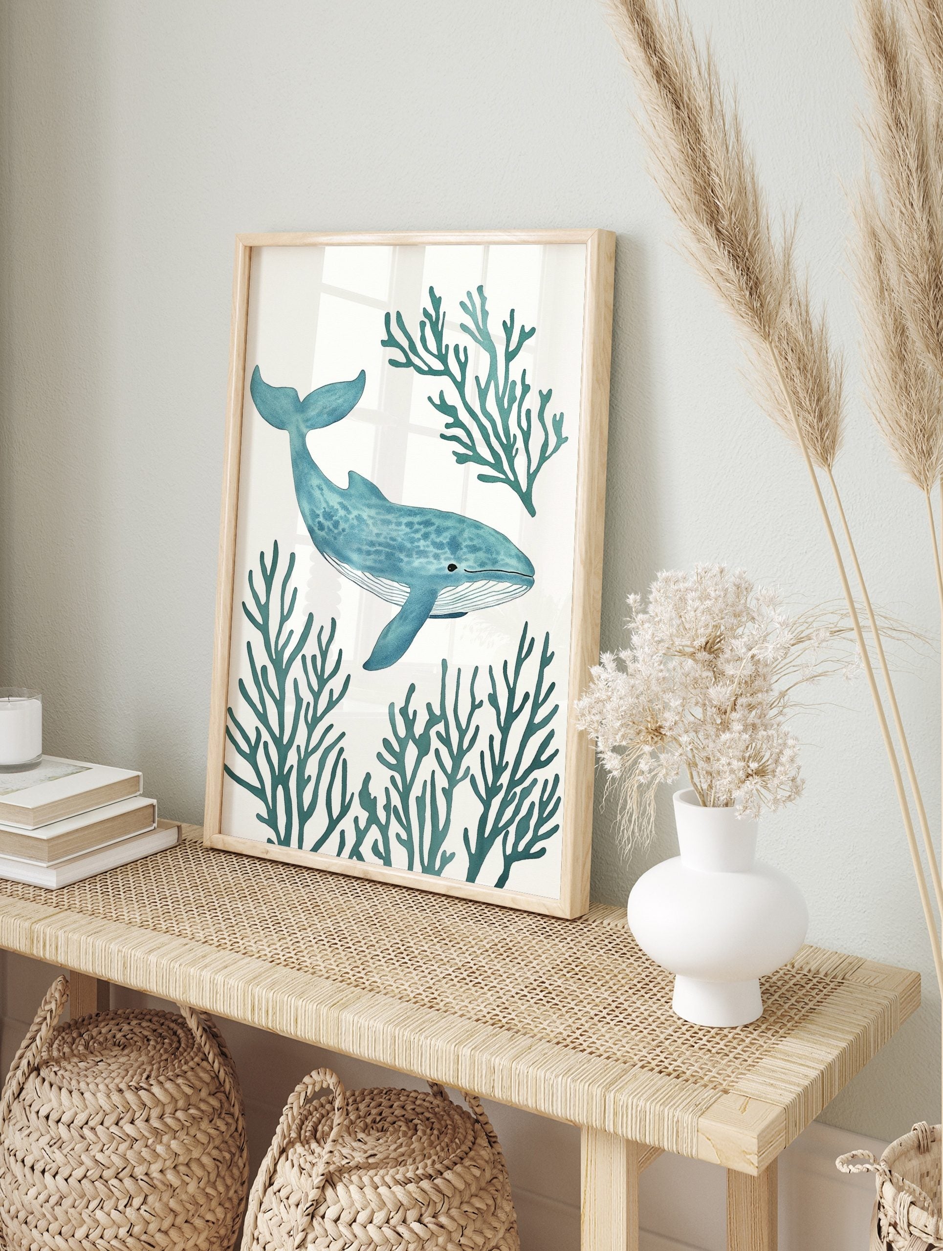 Blue whale with stippled texture swimming amidst teal coral branches on a white background, in an alternate framed mockup