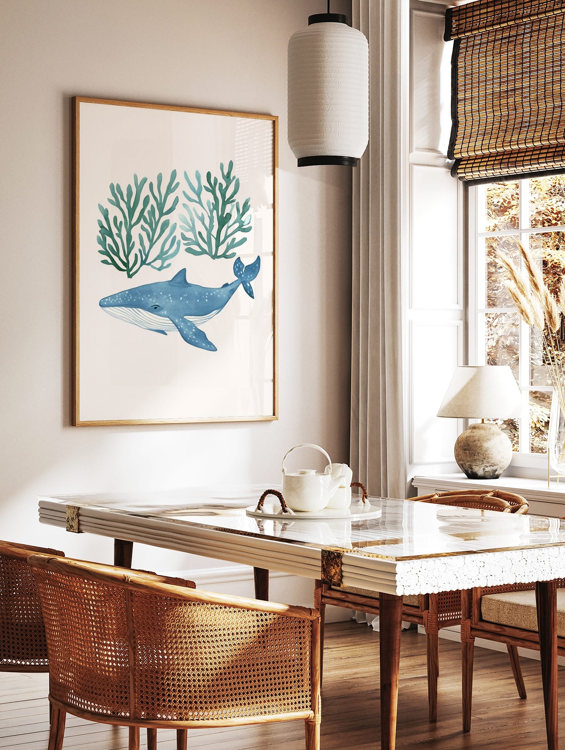 Watercolour illustration of a blue whale with white spots swimming below two clusters of teal, in a styled room mockup