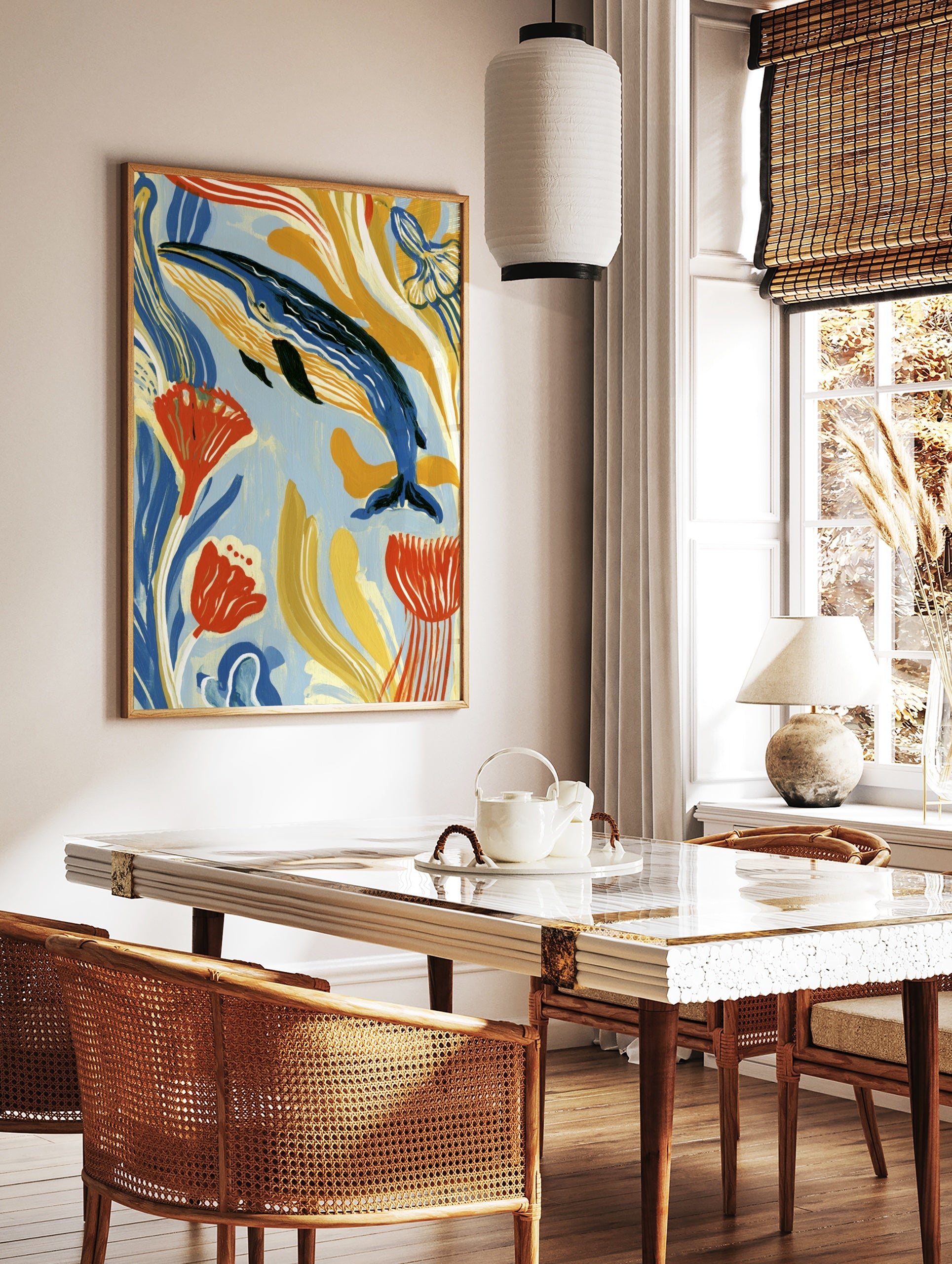 Blue whale swimming among stylized yellow and orange seaweed, modern illustrative ocean art print, in a styled room mockup
