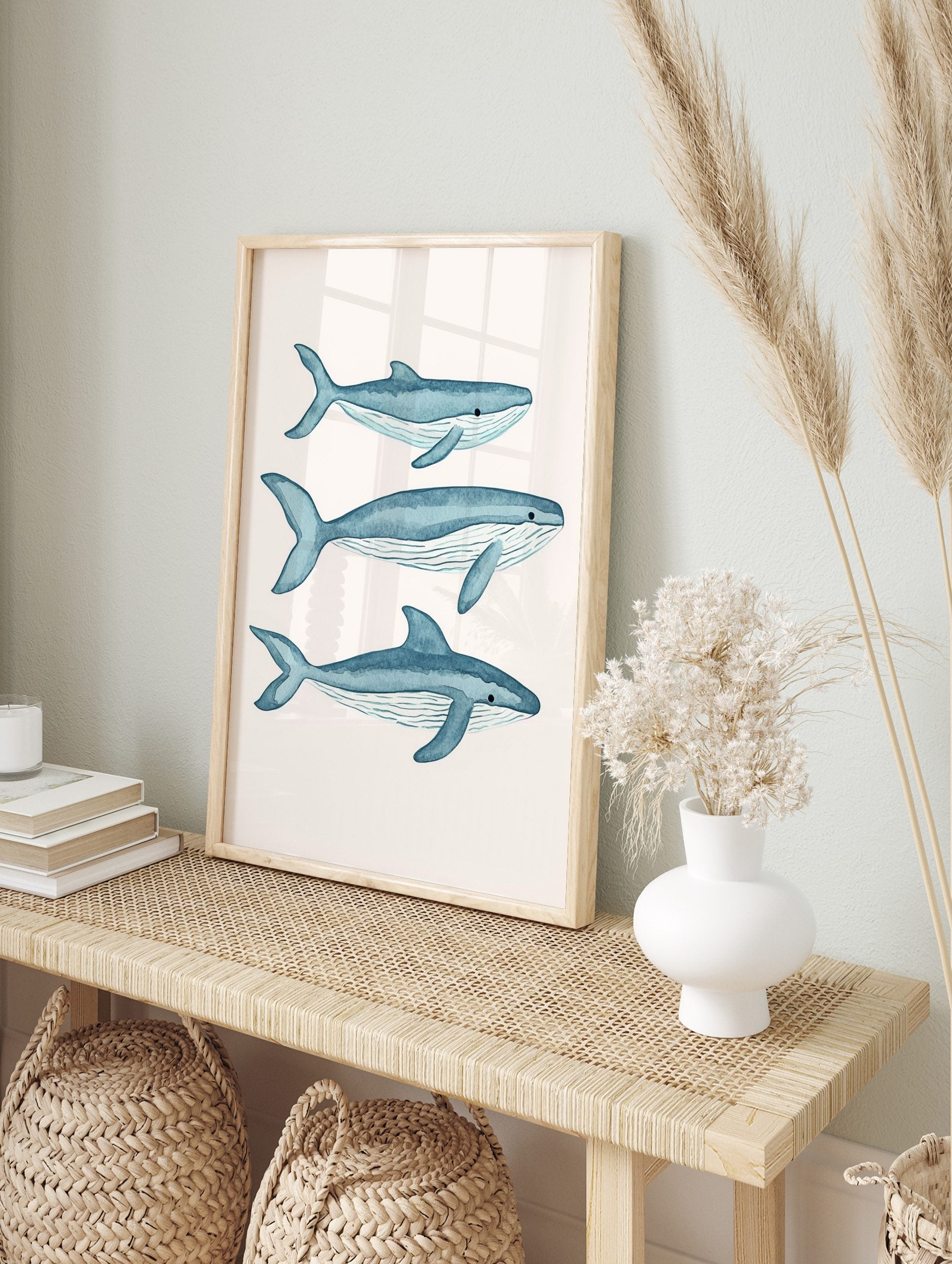 Three blue watercolour whale illustrations, swimming right on a white background, with, in an alternate framed mockup