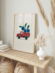 Red vintage pickup truck carrying a branch of blue blueberries and green leaves, illustrative, in an alternate framed mockup