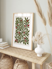 Botanical illustration print of green leafy branches with red berries on a cream background, in an alternate framed mockup