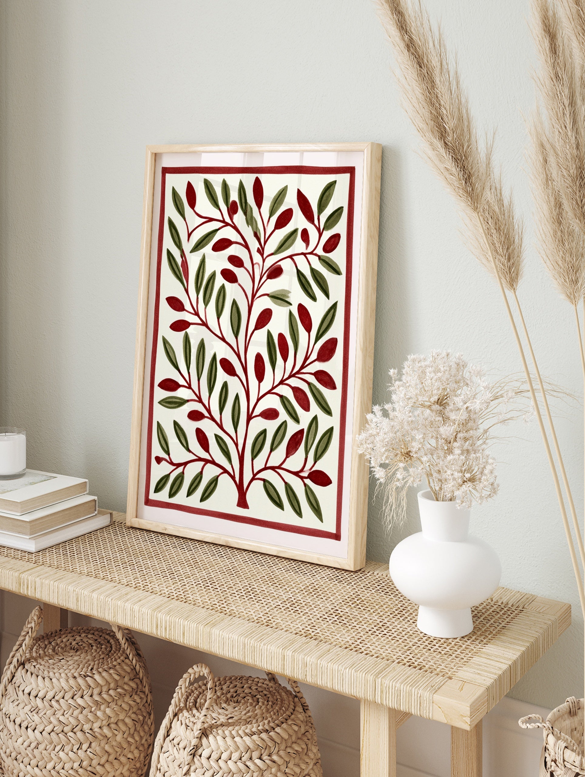 Stylised botanical illustration with green leaves and red berries inside a red border on a, in an alternate framed mockup