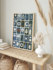 Grid artwork with cats, flowers, pottery, and celestial symbols in blue, white, and brown on, in an alternate framed mockup