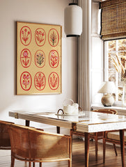 Botanical grid wall art print featuring nine red floral and leaf illustrations inside oval frames, in a styled room mockup