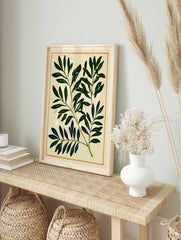Botanical leaf print with deep green foliage and thin orange border on cream paper background, in an alternate framed mockup
