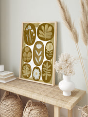 Botanical wall art print with eight oval floral and leaf illustrations in white against a, in an alternate framed mockup