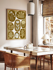Botanical wall art print with eight oval floral and leaf illustrations in white against a warm gold, in a styled room mockup