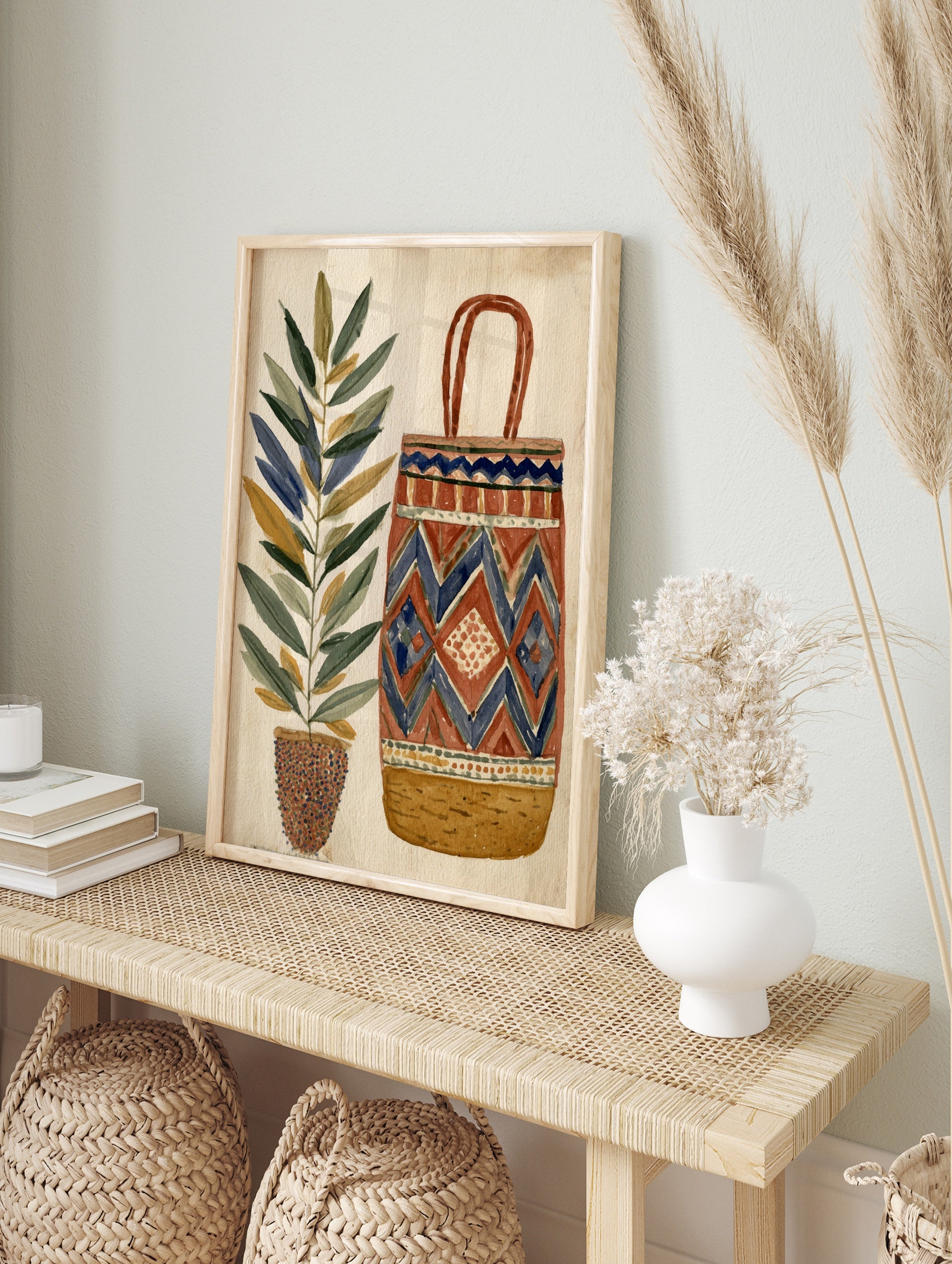 Illustrative wall art print of a tall potted plant next to a geometric patterned woven basket, in an alternate framed mockup