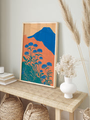 Illustrative botanical wall art with blue flowers, green leaves, orange hills, and a blue mountain under a light orange sky. - Image 3