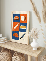 Bakery themed wall art print with bread, croissant, butter, and kitchen tools in a blue and, in an alternate framed mockup