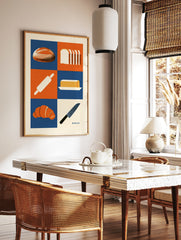 Bakery themed wall art print with bread, croissant, butter, and kitchen tools in a blue and orange, in a styled room mockup