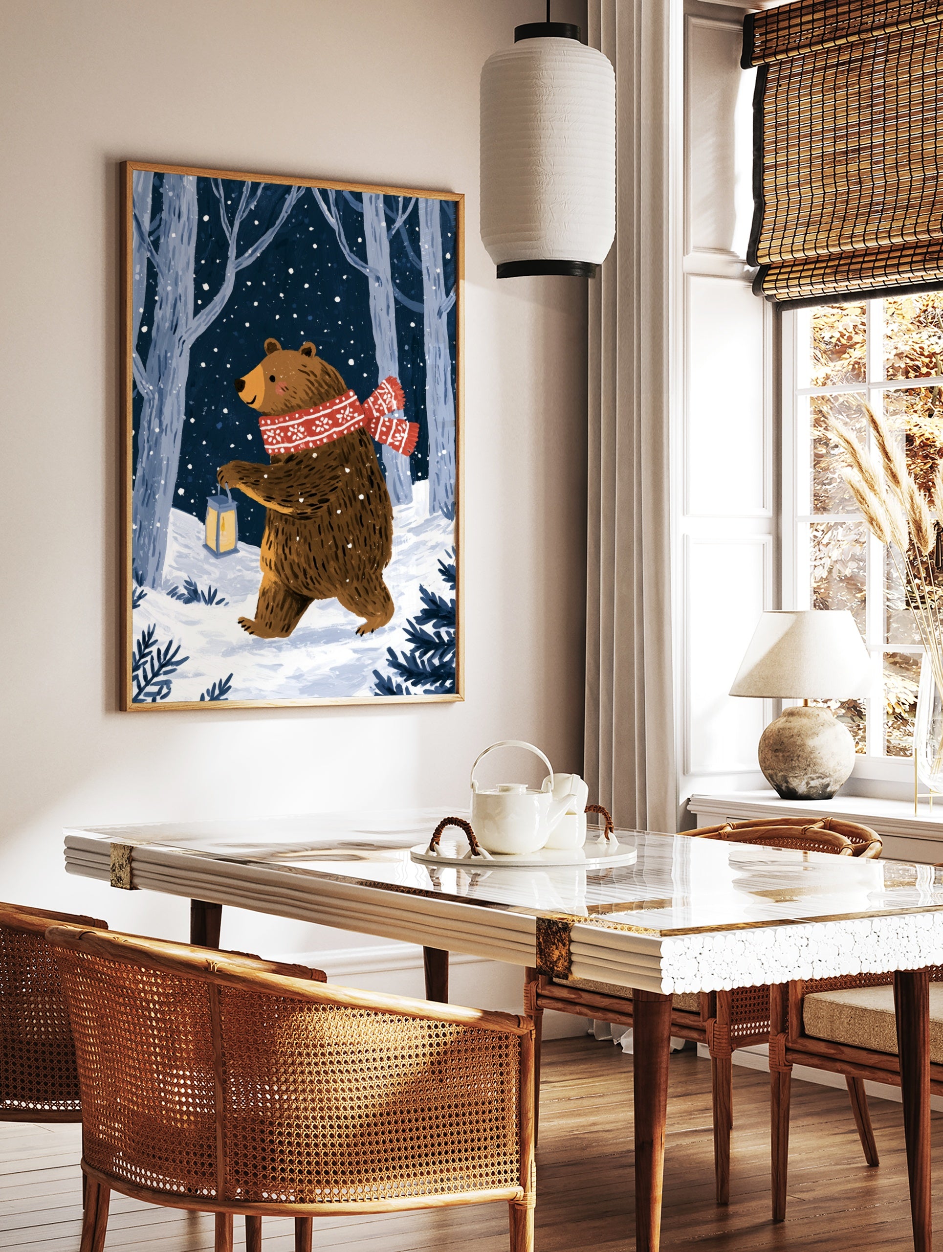 Illustrative print of a brown bear with a red scarf and lantern in a snowy forest at night, in a styled room mockup