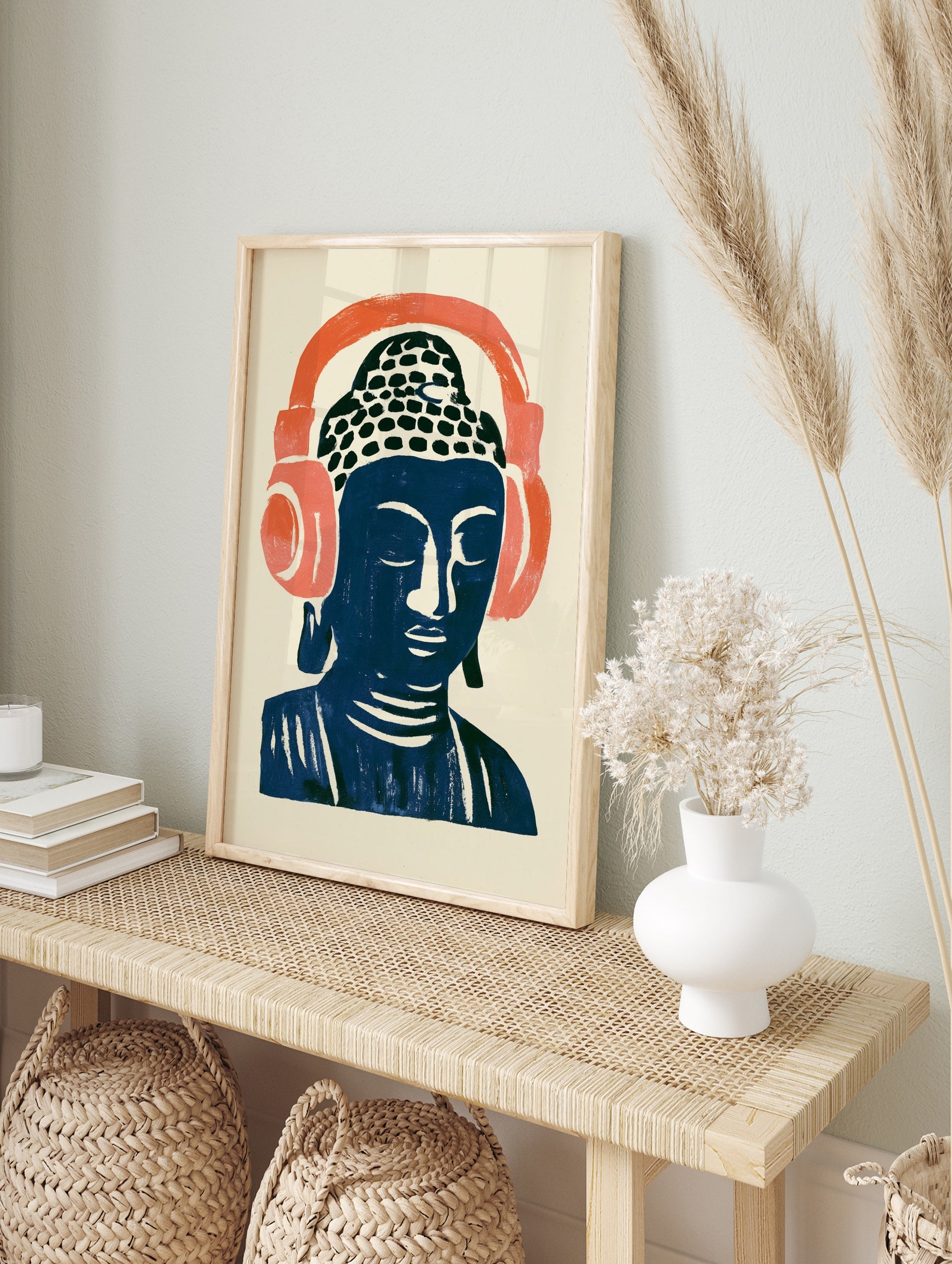 Stylized Buddha head illustration wearing large coral headphones on a cream background, in an alternate framed mockup