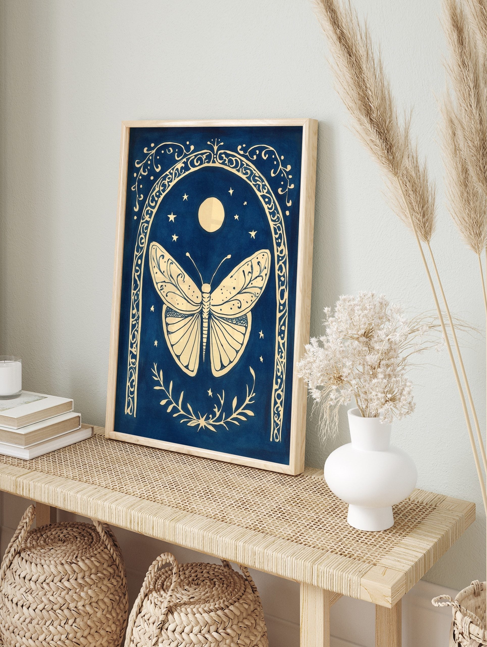 Ornate cream butterfly within a decorative arch, with moon and stars on a deep blue background, in an alternate framed mockup