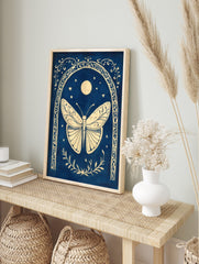Ornate cream butterfly within a decorative arch, with moon and stars on a deep blue background, in an alternate framed mockup