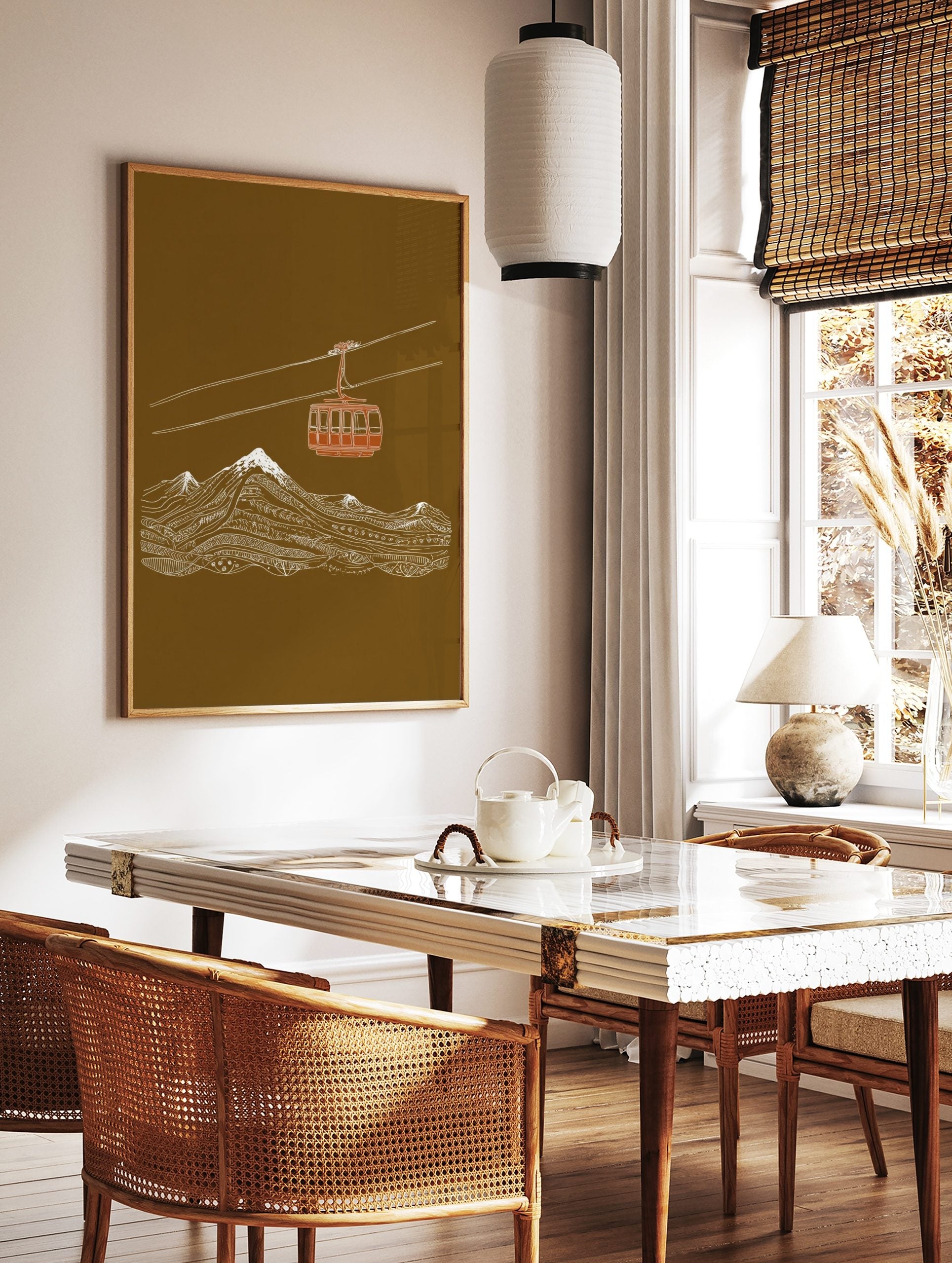 Illustrative art print of a red cable car over white snow-capped mountains on a brown background, in a styled room mockup