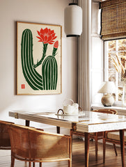 Illustrative cactus wall art with a vibrant red flower and bud on a textured cream background with, in a styled room mockup