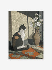 Illustrative calico cat wall art print sitting next to a vase of white flowers, with sunlight casting shadows on patterned wallpaper.