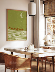Illustrative camel caravan with six riders crossing sand dunes under a green night sky with moon, in a styled room mockup