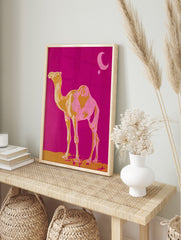 Golden yellow and pink camel standing on sand against fuchsia sky with moon and star, in an alternate framed mockup