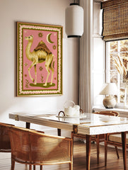 Illustrative camel with ornate saddle, crescent moon, and stars on pink background with green border, in a styled room mockup