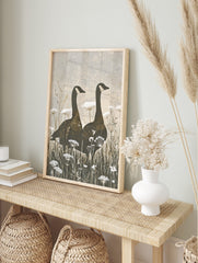 Two Canada geese silhouettes stand in a field of white Queen Anne's Lace flowers, earthy, in an alternate framed mockup