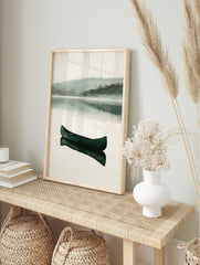 Dark green canoe floating on a calm, misty lake with reflection, minimalist watercolor, in an alternate framed mockup