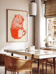 Orange ink illustration of a capybara sitting inside a teacup on off-white paper, in a styled room mockup