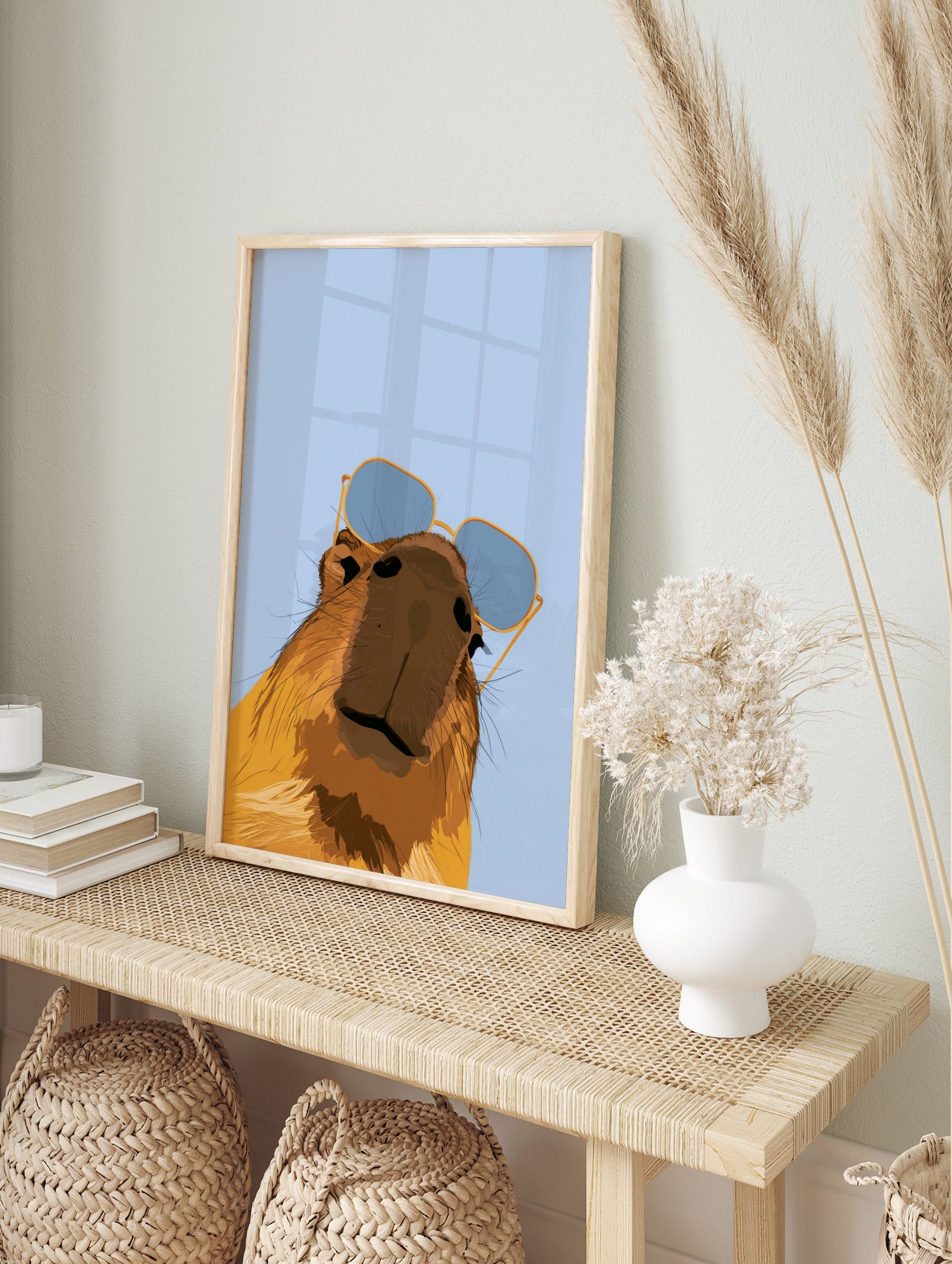 Stylised capybara illustration wearing blue-tinted sunglasses against a light blue background, in an alternate framed mockup