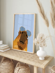 Stylised capybara illustration wearing blue-tinted sunglasses against a light blue background, in an alternate framed mockup