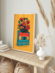 Retro cassette tape with vibrant orange and red flowers bursting from the top, illustrative, in an alternate framed mockup